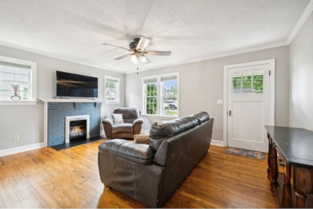 living room with dark hardwood / wood-style flooring, a brick fireplace, a textured ceiling, ceiling fan, and crown molding