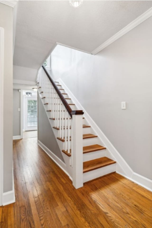 stairway with hardwood / wood-style flooring and crown molding