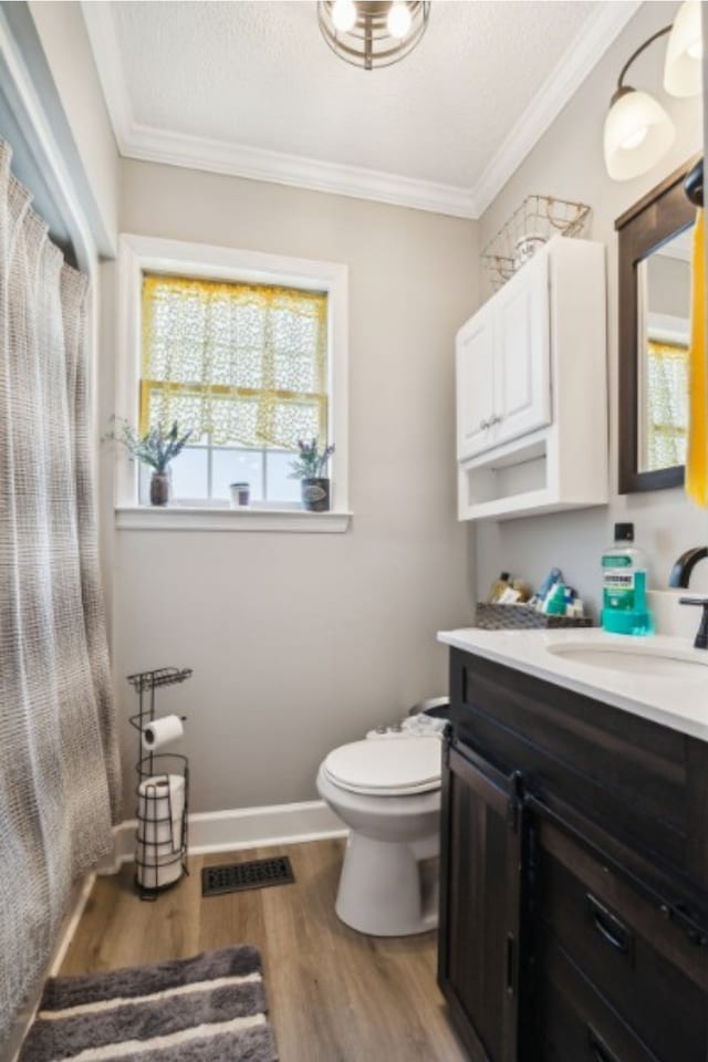 bathroom with toilet, hardwood / wood-style floors, vanity, and ornamental molding