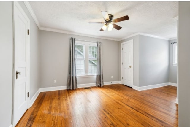 empty room featuring hardwood / wood-style floors, a textured ceiling, ceiling fan, and ornamental molding