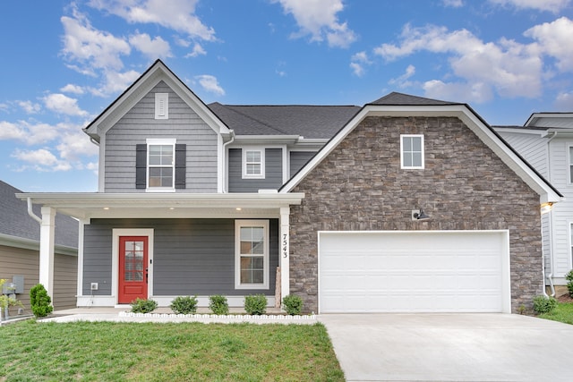 view of property featuring covered porch, a garage, and a front yard