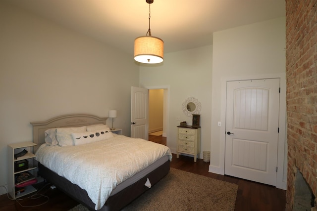 bedroom with dark hardwood / wood-style flooring and brick wall