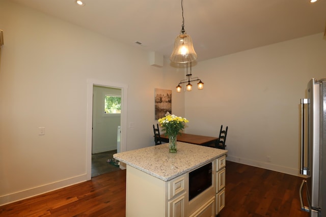 kitchen with built in microwave, dark wood-type flooring, a center island, stainless steel refrigerator, and hanging light fixtures