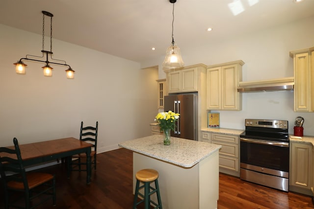 kitchen with appliances with stainless steel finishes, dark hardwood / wood-style flooring, cream cabinets, a center island, and hanging light fixtures