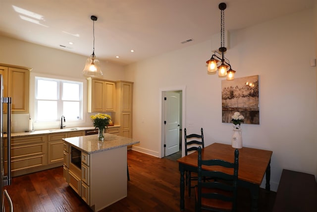 kitchen featuring a center island, sink, hanging light fixtures, dark hardwood / wood-style floors, and light stone countertops