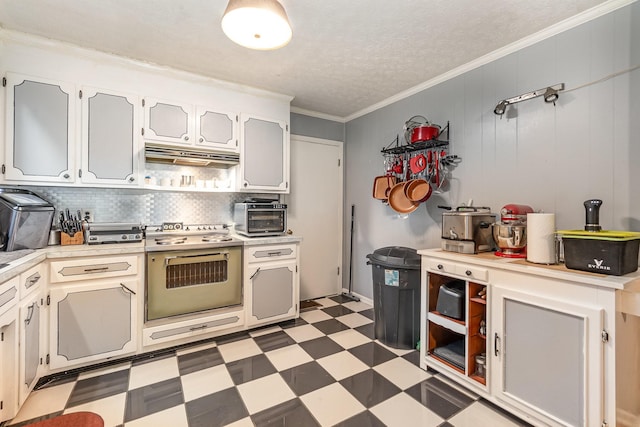 kitchen with white cabinetry, stainless steel oven, crown molding, wood walls, and decorative backsplash