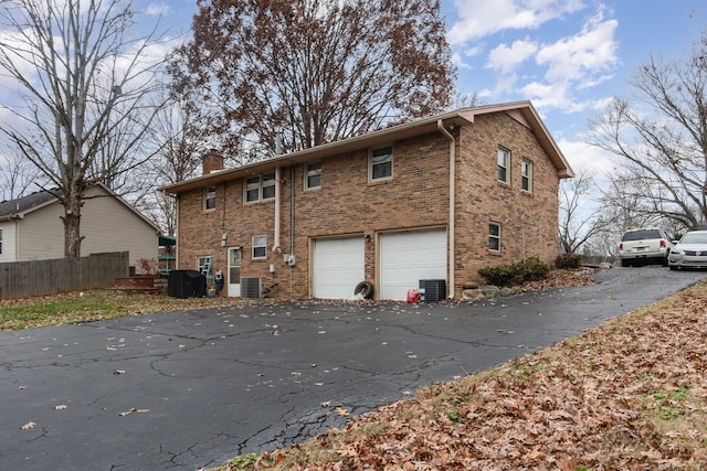 back of house with central AC unit and a garage