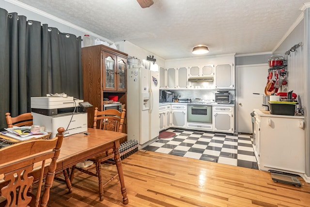 kitchen with tasteful backsplash, a textured ceiling, appliances with stainless steel finishes, exhaust hood, and ornamental molding