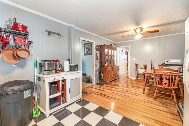 dining room with a textured ceiling, ceiling fan, crown molding, hardwood / wood-style flooring, and wood walls