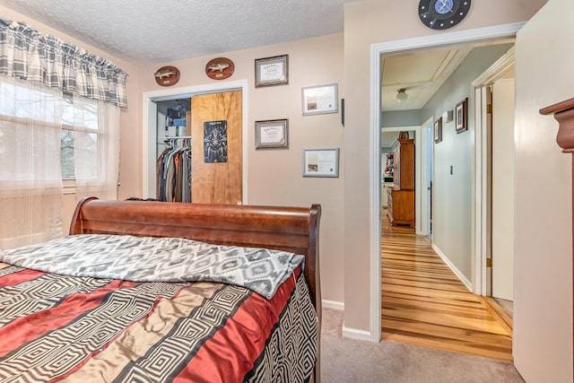 bedroom featuring a textured ceiling, a spacious closet, light hardwood / wood-style flooring, and a closet