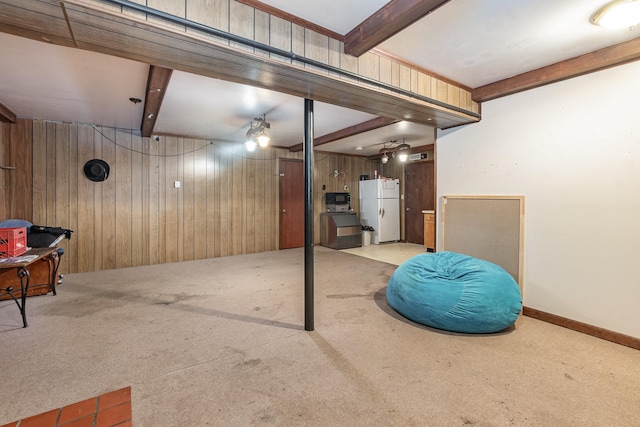 basement featuring white fridge, wooden walls, and light colored carpet