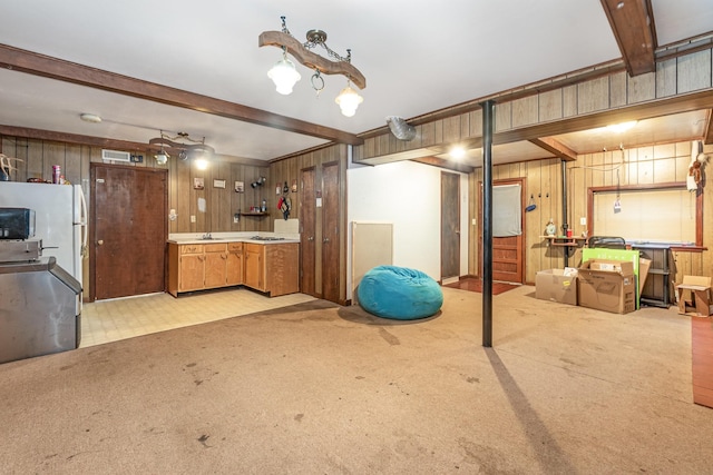 interior space featuring light carpet, white refrigerator, wooden walls, and sink