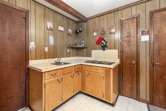 kitchen with sink, white gas cooktop, and wood walls