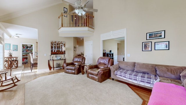 living room featuring ceiling fan, wood-type flooring, ornamental molding, and high vaulted ceiling