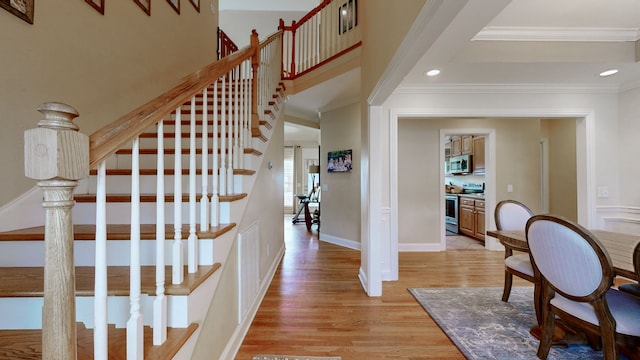 stairs with wood-type flooring and ornamental molding