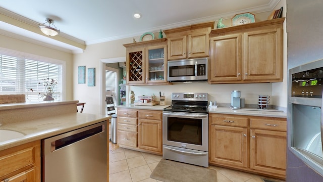 kitchen with stainless steel appliances, crown molding, and light tile patterned flooring