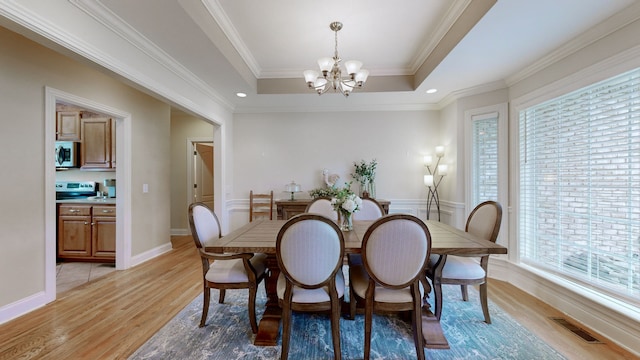 dining space with light hardwood / wood-style floors, a wealth of natural light, and crown molding