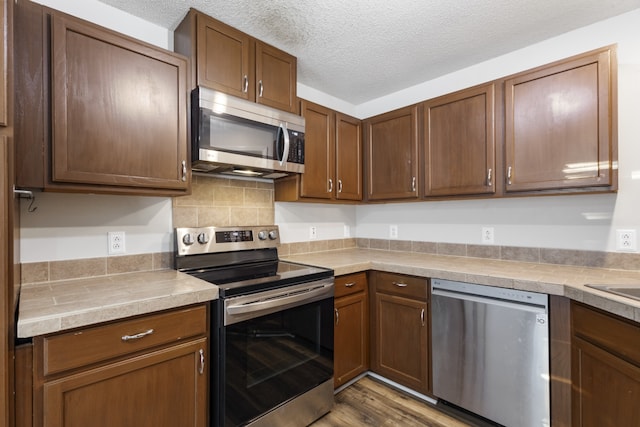 kitchen with a textured ceiling, stainless steel appliances, and hardwood / wood-style flooring