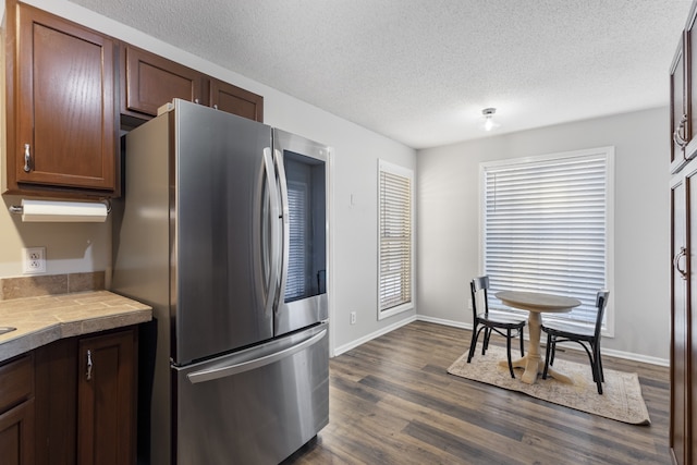 kitchen featuring a textured ceiling, stainless steel fridge, tile counters, and dark hardwood / wood-style floors