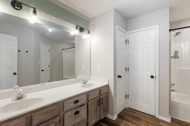 bathroom with wood-type flooring, vanity, a textured ceiling, and shower / bath combo with shower curtain