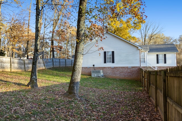 view of side of home with central AC and a lawn