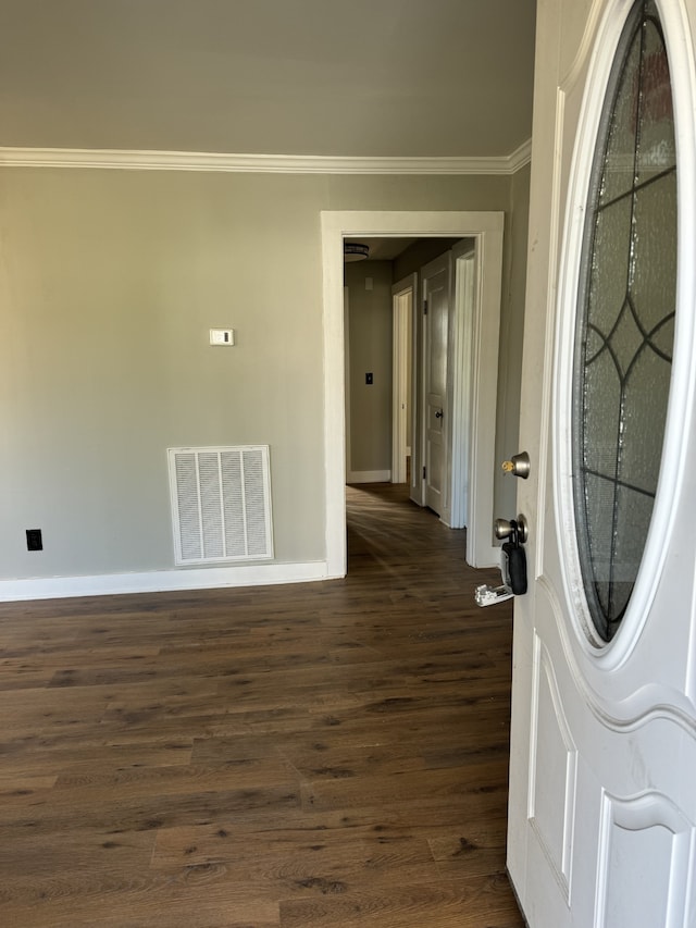 foyer entrance with baseboards, visible vents, dark wood-type flooring, and ornamental molding