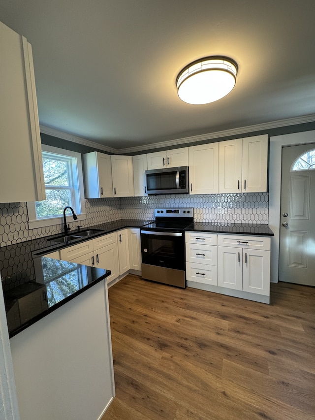 kitchen with dark countertops, white cabinetry, appliances with stainless steel finishes, and a sink