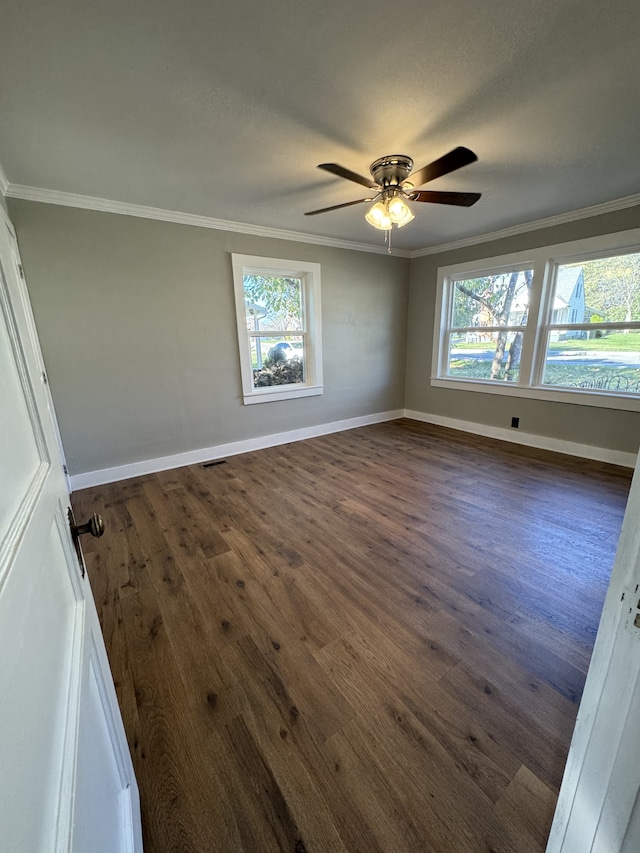 unfurnished room with plenty of natural light, ornamental molding, and dark wood finished floors