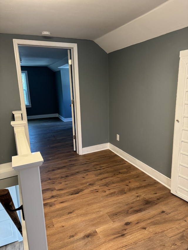 empty room featuring dark wood-style floors, lofted ceiling, and baseboards