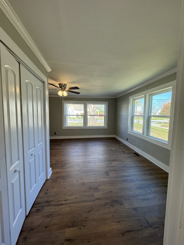 interior space featuring plenty of natural light, ornamental molding, and dark wood finished floors