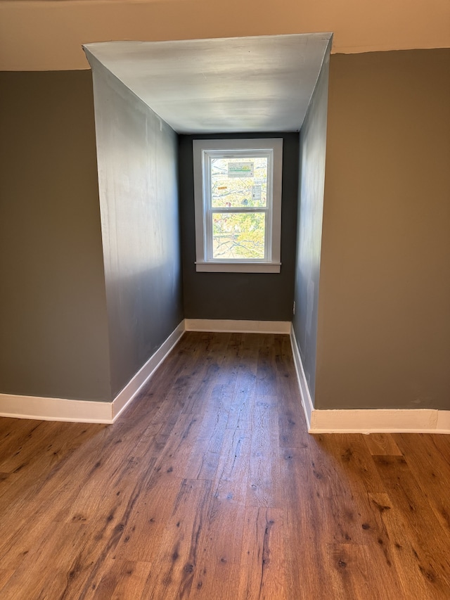 spare room featuring dark wood-style flooring and baseboards