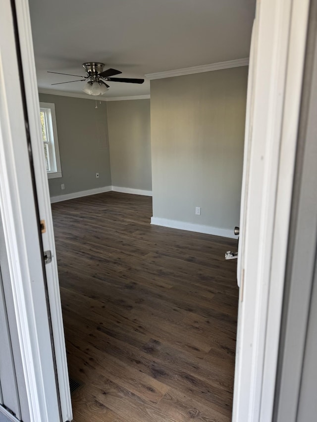 unfurnished room featuring ornamental molding, dark wood-style flooring, ceiling fan, and baseboards