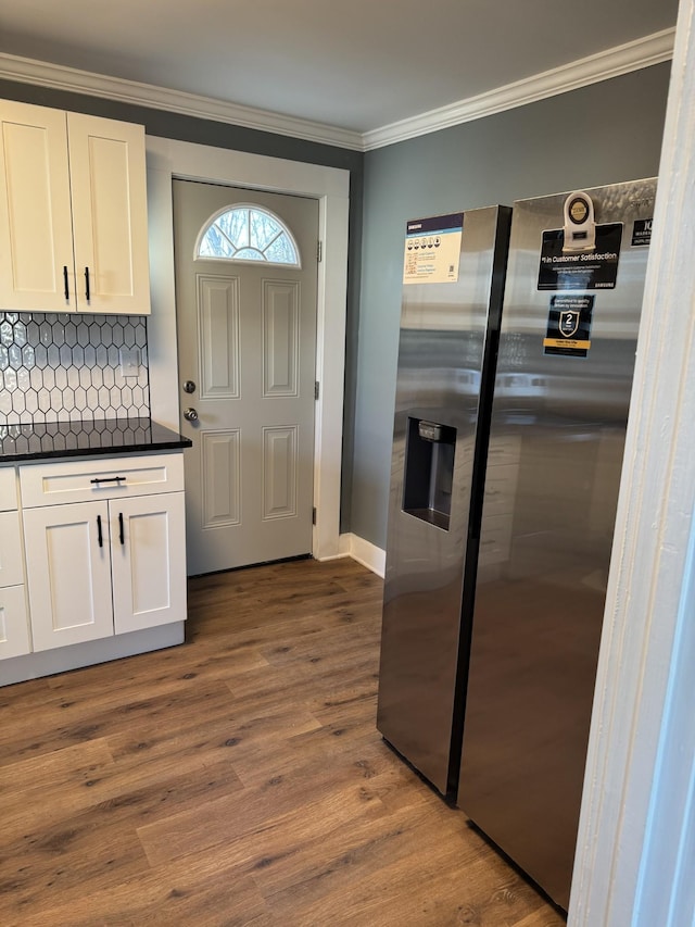 kitchen featuring wood finished floors, white cabinets, dark countertops, stainless steel fridge, and crown molding