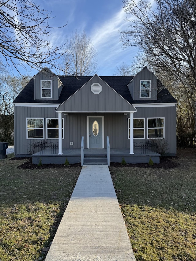 bungalow with a shingled roof, a front lawn, a porch, and board and batten siding