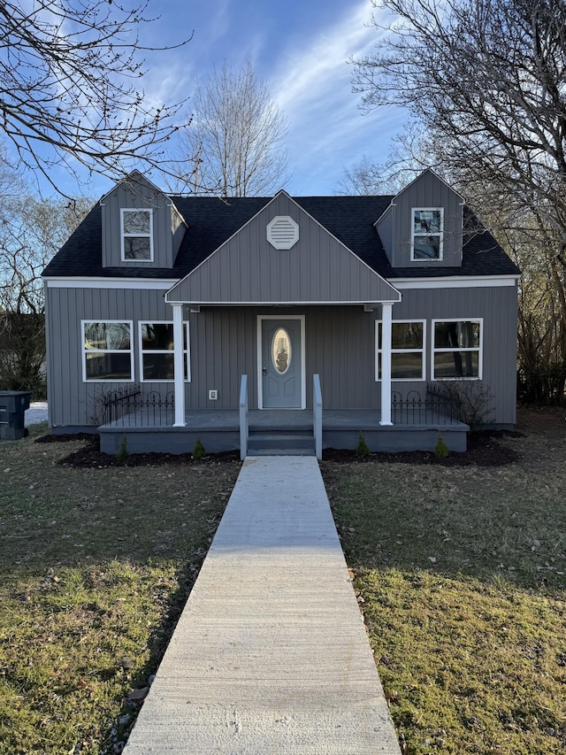 bungalow-style home with a shingled roof, a front yard, covered porch, and board and batten siding