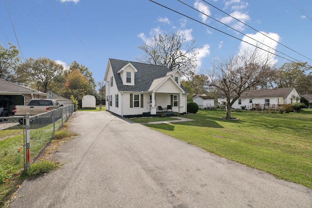 cape cod-style house featuring covered porch and a front lawn