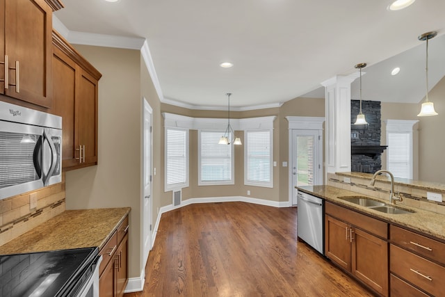 kitchen featuring pendant lighting, light stone countertops, sink, and appliances with stainless steel finishes