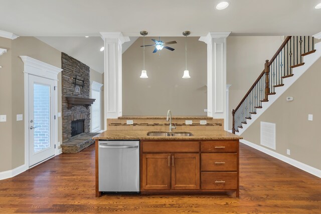 kitchen featuring pendant lighting, dark wood-type flooring, sink, stainless steel dishwasher, and a fireplace