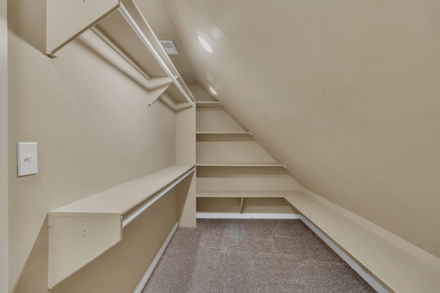 spacious closet with light colored carpet and vaulted ceiling