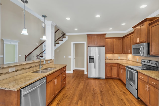 kitchen with sink, hanging light fixtures, dark hardwood / wood-style floors, light stone counters, and stainless steel appliances