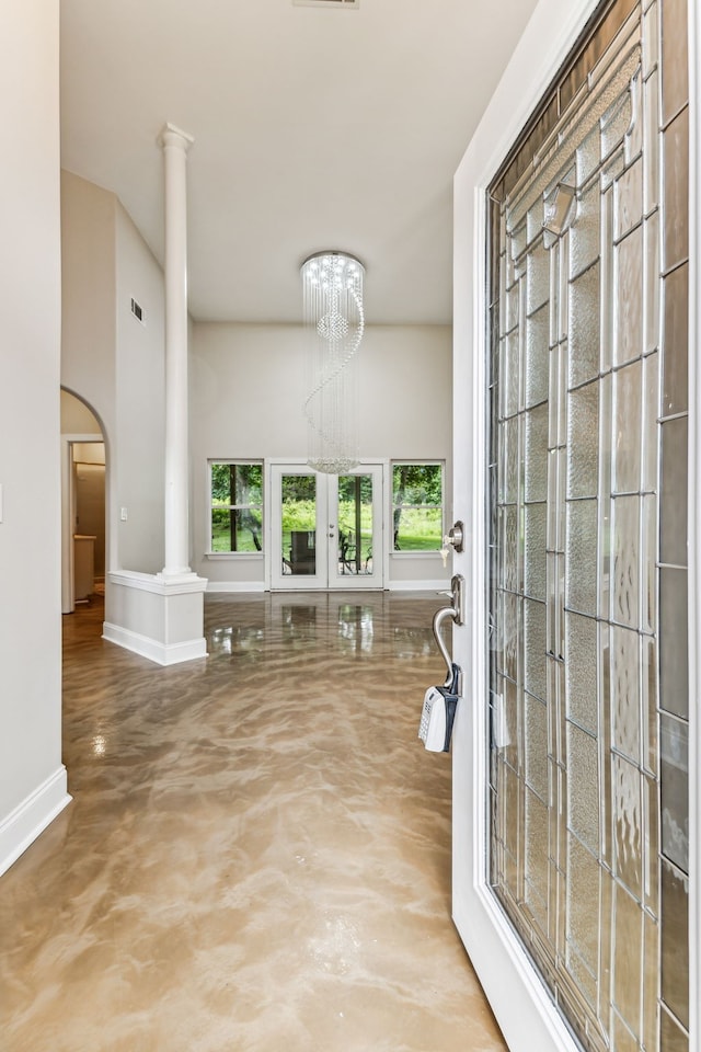 foyer entrance with a notable chandelier, french doors, and concrete floors