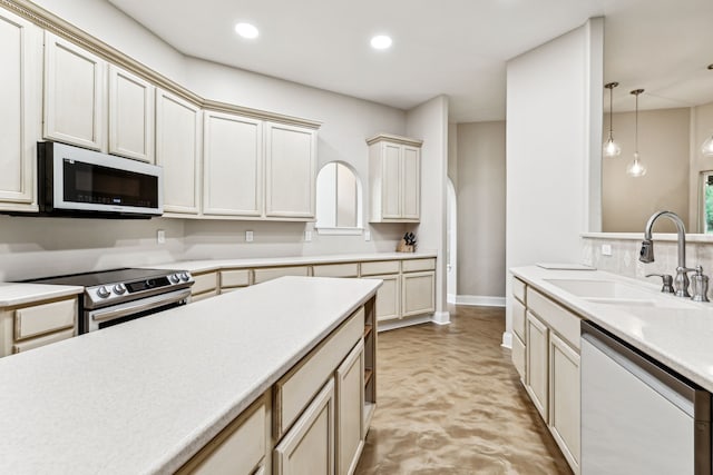 kitchen featuring sink, cream cabinetry, pendant lighting, and appliances with stainless steel finishes