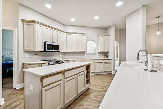 kitchen featuring cream cabinetry, appliances with stainless steel finishes, decorative light fixtures, and sink