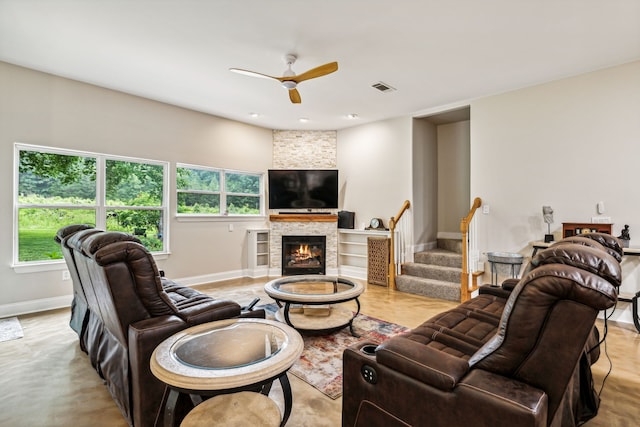 living room with ceiling fan and a stone fireplace