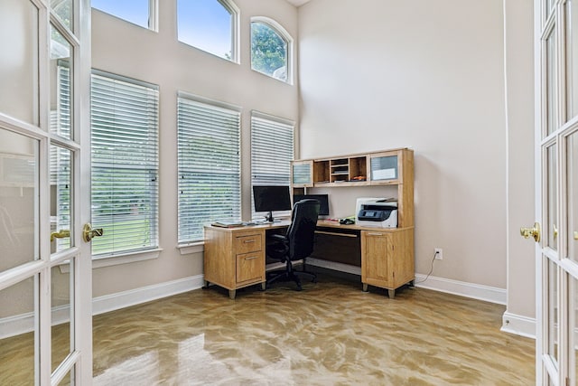 office featuring french doors, a towering ceiling, and light colored carpet