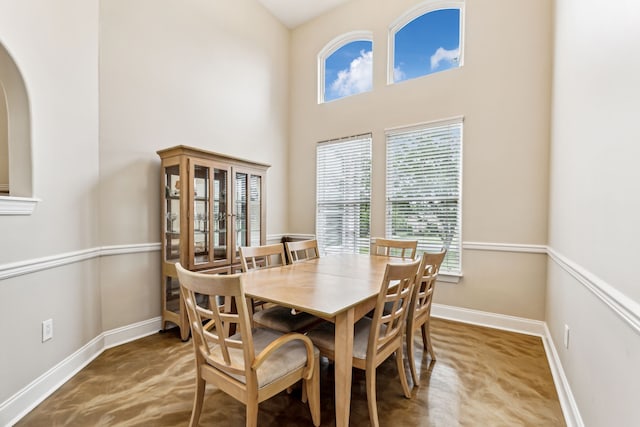 dining space with carpet, plenty of natural light, and a towering ceiling