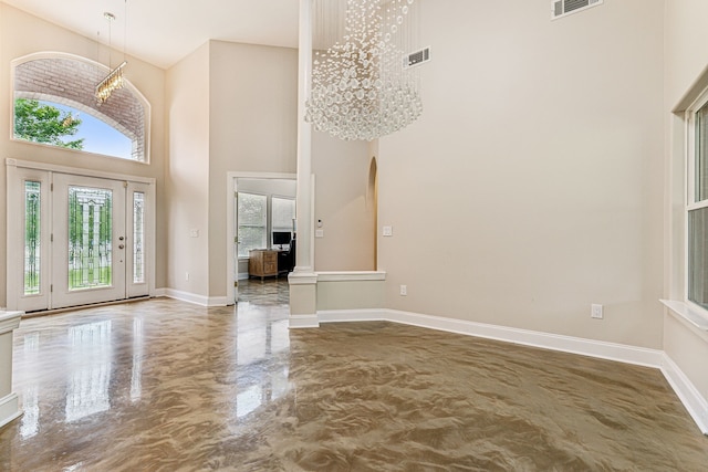 entryway with concrete floors, a towering ceiling, and a chandelier