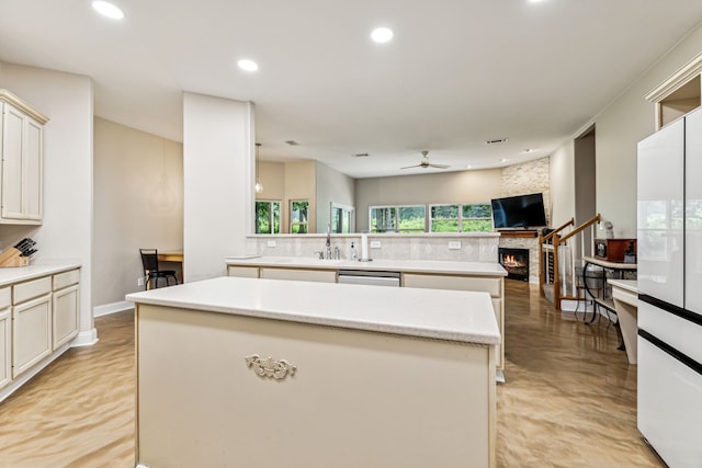 kitchen featuring a stone fireplace, ceiling fan, a center island, and decorative backsplash