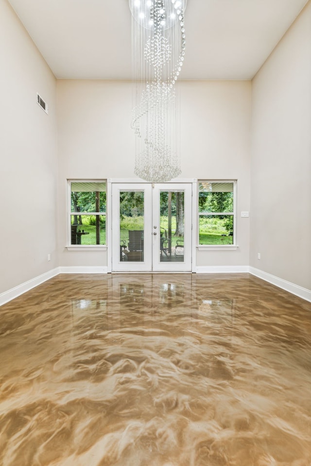 unfurnished living room featuring a notable chandelier, a wealth of natural light, and french doors