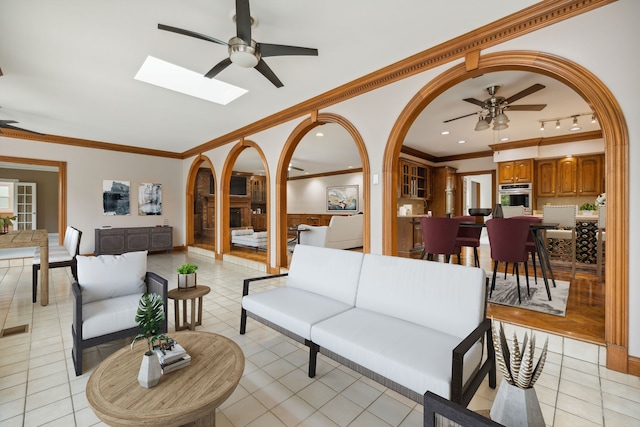 living room with a skylight, crown molding, and light tile patterned floors